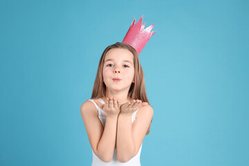 Cute girl in pink crown on light blue background. Little princess © New Africa