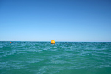 Fototapeta na wymiar Yellow buoy floating on sea surface as marker for swimming restriction in deep water at tropical resort. Human life safety concept