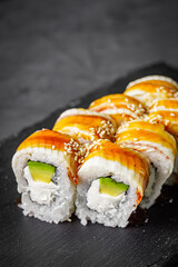 appetizing Philadelphia sushi roll with eel and avocado on a black stone plate