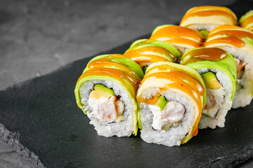 appetizing green dragon sushi roll with philadelphia cucumber shrimp and avocado on a black stone plate