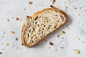 Fresh homemade bread (slice) from whole grain sourdough flour with the addition of bran, seeds (sunflower, pumpkin, flax, sesame) and oatmeal flakes. Healthy food. High quality photo. - obrazy, fototapety, plakaty