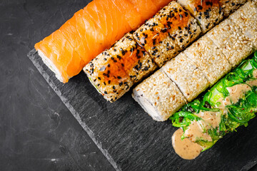 appetizing set of sushi roll on a black stone plate