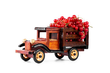 Ripe red currnat in wooden toy truck on white background.