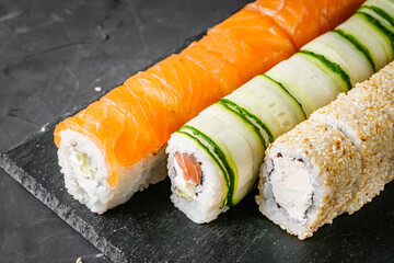 appetizing set of sushi roll on a black stone plate