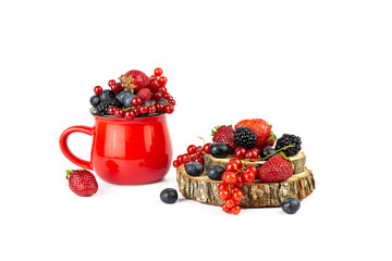 Ripe berries mixed assortment in red cup and wooden board or podium with berry on white background. Summer or Spring Organic Berry background.