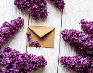 Purple lilac and envelope on a white wooden background. place for text.Flat lay