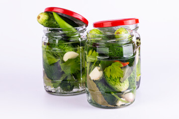 Pickled cucumbers in glass jar on white background.