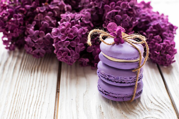 purple macaroons and lilacs on a white wooden background. place for text