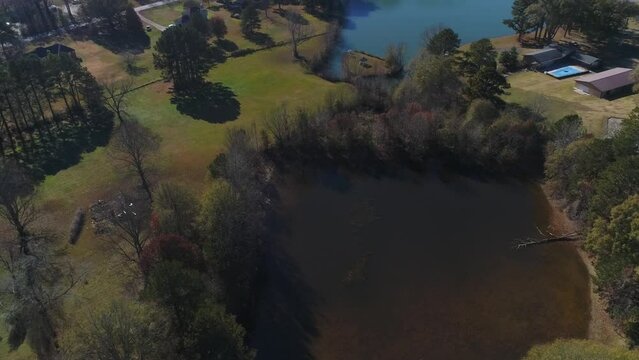 Aerial circle view of brown lake to reveal two lakes with green trees