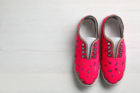 Amazing customized shoes on white wooden background, flat lay. Space for text