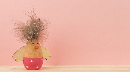 One Easter decorative wooden chicken figurine on pink background with copy space. Minimal concept for Easter.