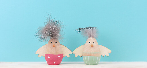 Two Easter decorative wooden chickens figurine on blue background with copy space. Minimal concept for Easter.