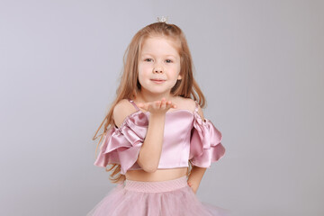 Cute girl in beautiful dress with small crown on light grey background. Little princess