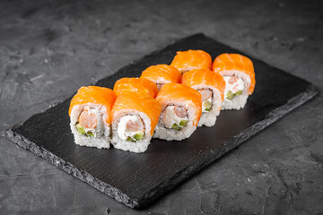 appetizing sushi roll philadelphia with shrimp cheese cucumber and salmon on a black stone plate