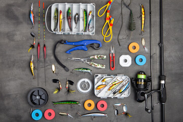 Fishing tackle - fishing spinning rod, hooks and lures on gray background. Active hobby recreation...