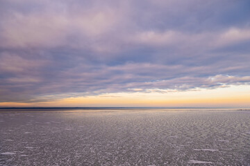 Heavy, dramatic sky over a frozen river. Frozen river at sunset.