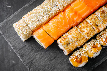 appetizing set of sushi roll on a black stone plate