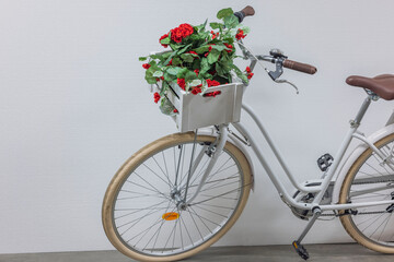 Fototapeta na wymiar Close up view of unusual cute white bicycle decorated with red artificial flowers in wooden box. Sweden. 