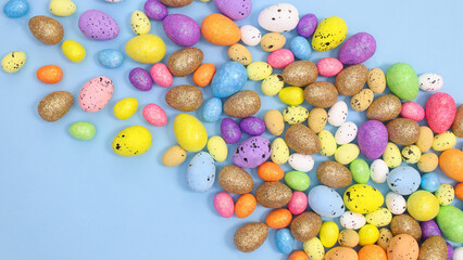 Pile of colorful eggs for Easter on bright pastel blue background. Flat lay creative arrangement. Spring holidays aesthetic