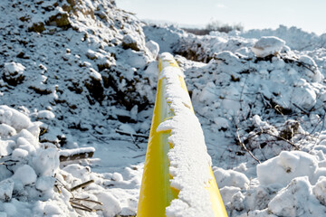 The yellow gas pipe is covered with snow.
