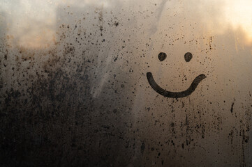 Cute smiley, smiling, painted on the window over blurred background, dew and drops of water, rain, morning in the warm rays, happy when his rainy weather is a beautiful art. Place for inscription.