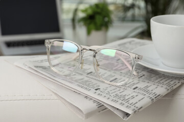 Newspapers, glasses and cup of drink on armrest indoors