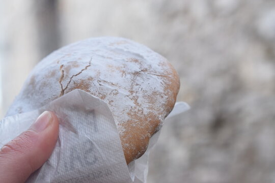 Ericino, a type of traditional dessert from Erice (Sicily) with icing sugar filled with lemon cream, held in the hand 