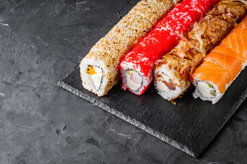 appetizing set of sushi roll on a black stone plate