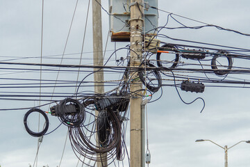 Chaos of cables and wires on an electric pole. Many electrical cable - wire and telephone line on electricity post. Cable breaks.