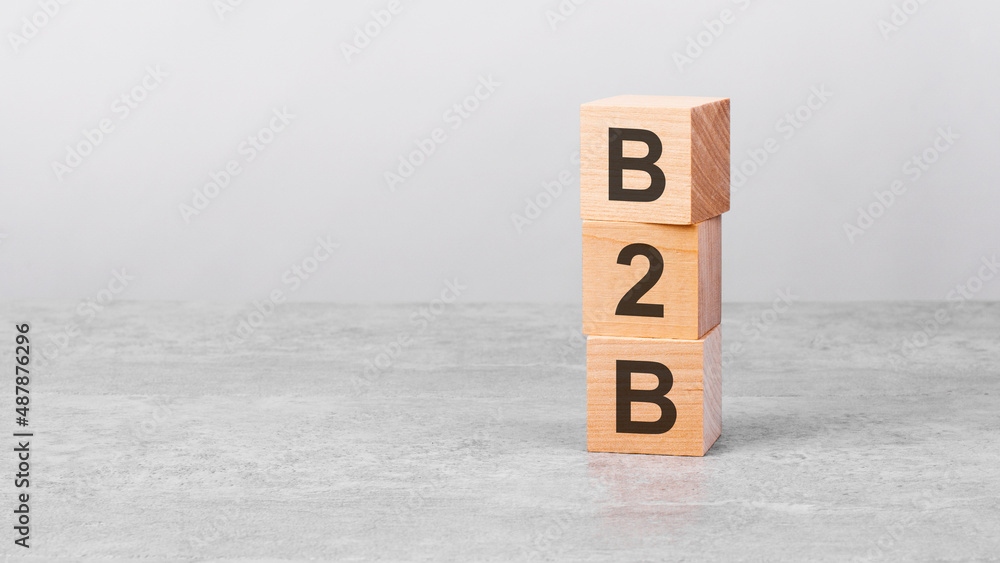 Aufkleber wooden cube on a table with text b2b. copy space on left for design, gray background