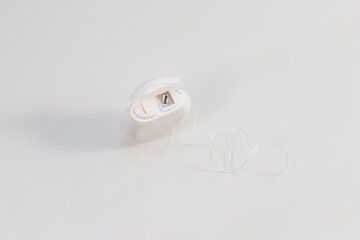 White box with dental floss lies on a white table.