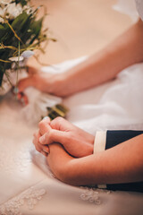 The bride and groom hold hands during the wedding ceremony in the church