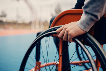 Close-up of man in wheelchair on an outdoor basketball court.