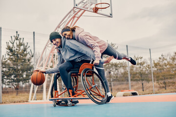 Playful couple has fun during a game on outdoor basketball court.