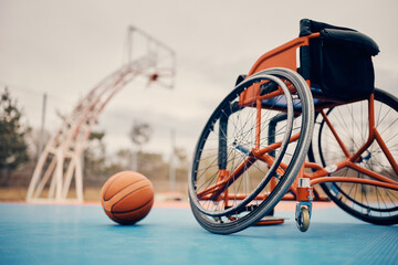 Sports wheelchair and basketball on outdoor sports court.