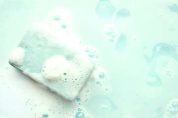 Soap bar and foam on blue background, top view. Mockup for design