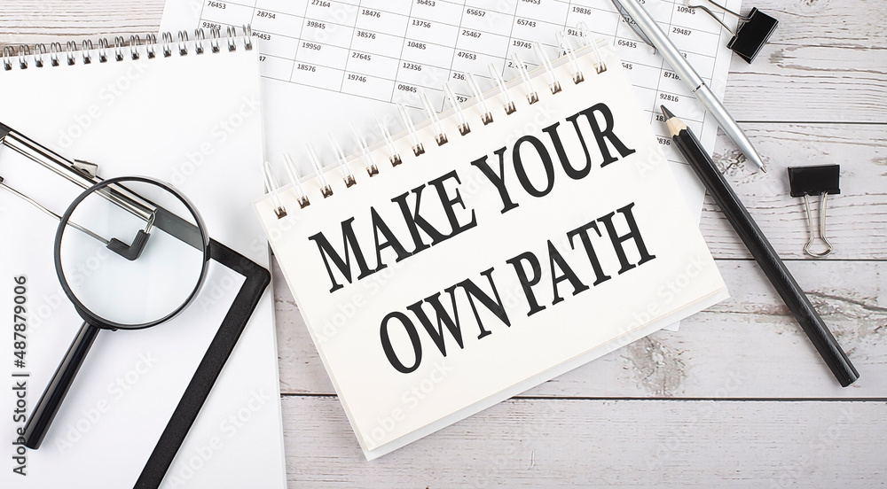 Aufkleber notepad with text make your own path with a pen,office tools and graphs on desktop.