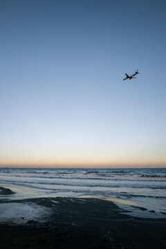 airplane flying over the beach in larnaca at sunset