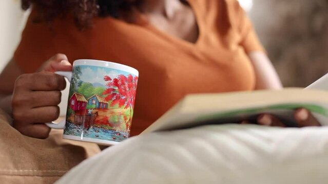 Dominican woman with curly hair reading a book and drinking coffee
