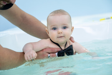 Fototapeta na wymiar russia, naberezhnye chelny-01.28.2022:a baby with a bow around his neck swims in a bath in a children's pool