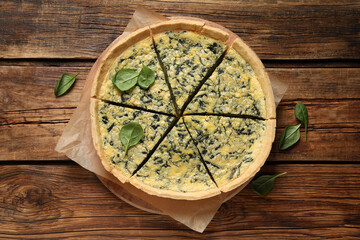 Cut delicious spinach pie on wooden table, top view