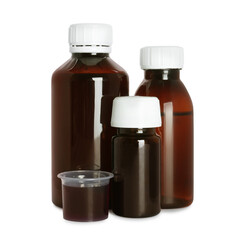 Bottles of cough syrup and measuring cup on white background