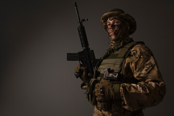 Soldier in a military camouflage uniform wearing a helmet, body armor, and holding a machine gun on...