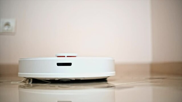 Working robotic vacuum cleaner at home, moving on the tile floor. Slow motion