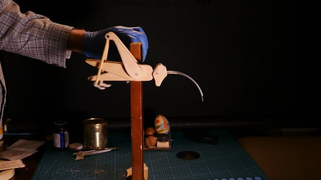 grasshopper wooden homemade toy in the hands of the master makes a somersault