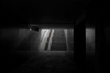Underground pedestrian crossing. Long concrete tunnel with lanterns in the city subway. Underpass, black and white photo