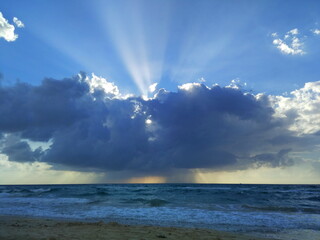 Naklejka na ściany i meble Sunset over the sea. Divine rays of the sun. Dramatic sunset on the beach. Beautiful sky