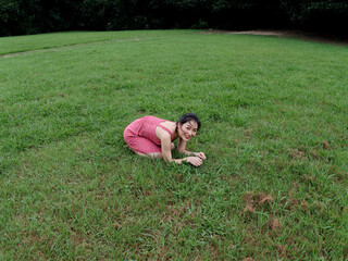 Portrait of young Asian woman kneel on grass field with barefoot in forest park, beautiful Chinese...