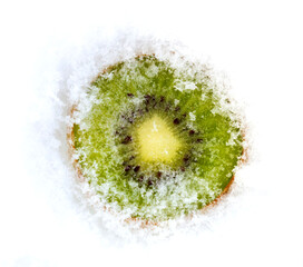 A slice of fresh green frozen kiwi fruit cowered with white cold winter snow.