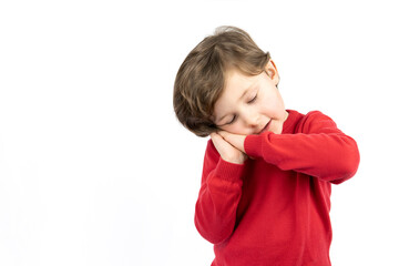 Tired kid with closed eyes leaning on palms as pillow pretending sleeping being exhausted seeing dreams standing against white background.